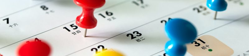 Thumb tack pins on calendar as reminder